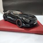 Sleek black 1:24 scale Mercedes-AMG GT Black Series style die-cast model car with its hood and doors open, showing red accents on the wheels and detailed grille. Khilone for kids
