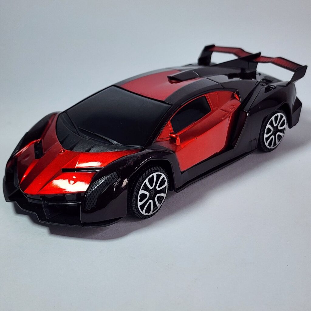 Black and metallic red RC Supercar model with large rear spoiler next to its black remote controller. Khilone for kids