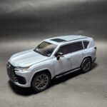 Light metallic silver 1:24 scale Lexus LX 600 SUV die-cast model car with a red interior, visible sunroof, and dark wheels. Khilone for kids