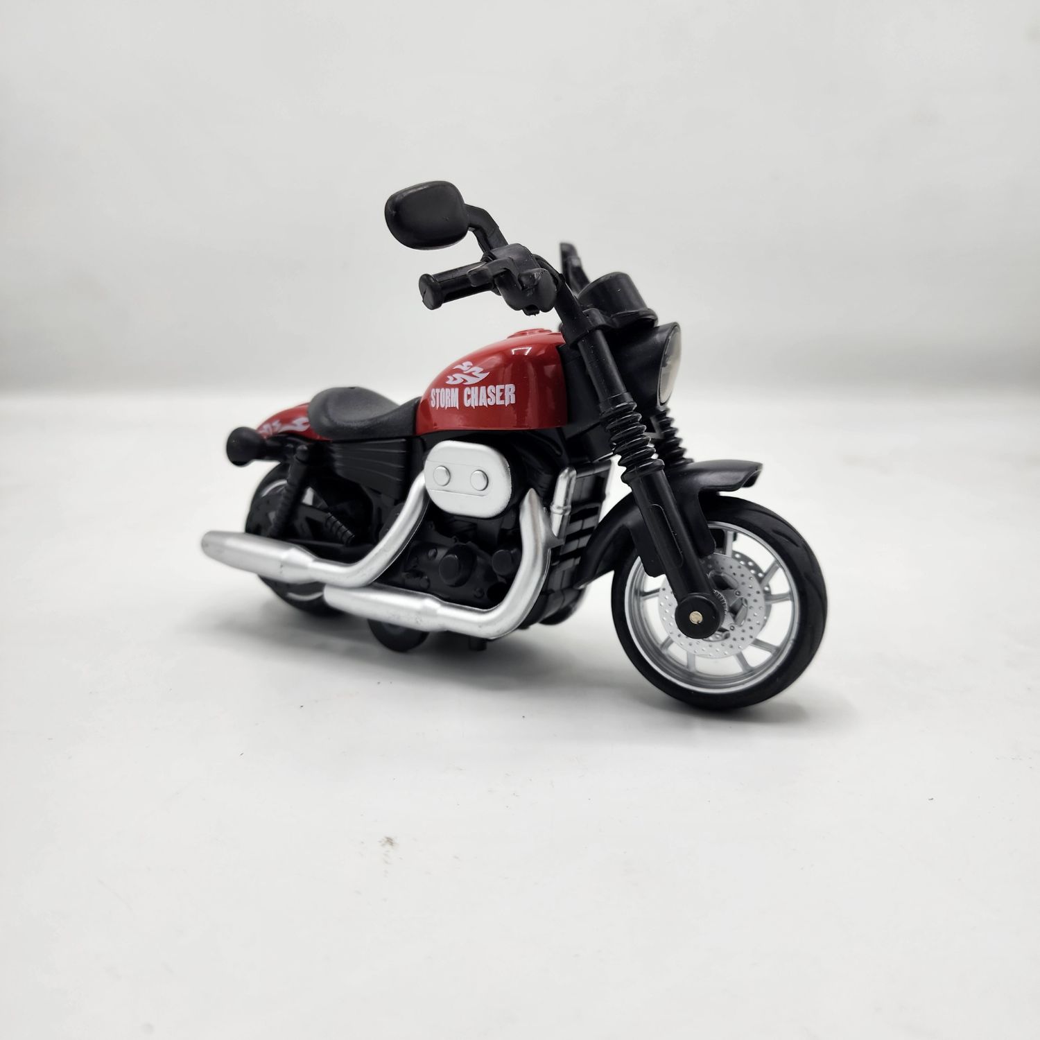 Red and black "Storm Chaser" cruiser motorcycle die-cast model with chrome-look exhaust pipes and detailed wheels on a white background. khilone for kids