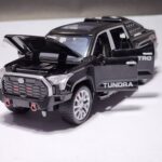 Black 1:32 scale Toyota Tundra TRD pickup truck die-cast model with all four doors, hood, and tailgate opened, showing the detailed interior and spare tire. Khilone for kids